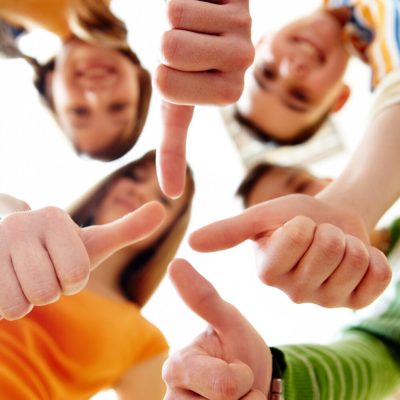 Below angle of happy teens showing thumbs up